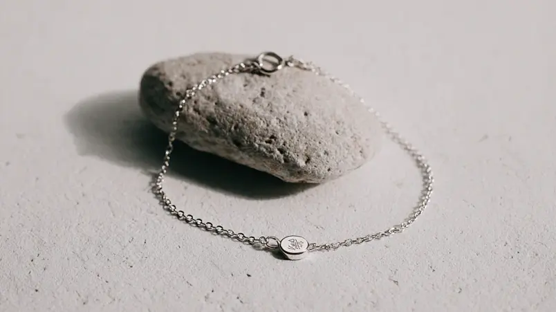 Silverarmband med graverat datum liggande på en enkel ljus yta som present till silverbröllop