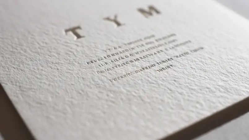 Närbild på bröllopsinbjudan tryckt med letterpress på tjockt bomullspapper med taktilt djup i texten