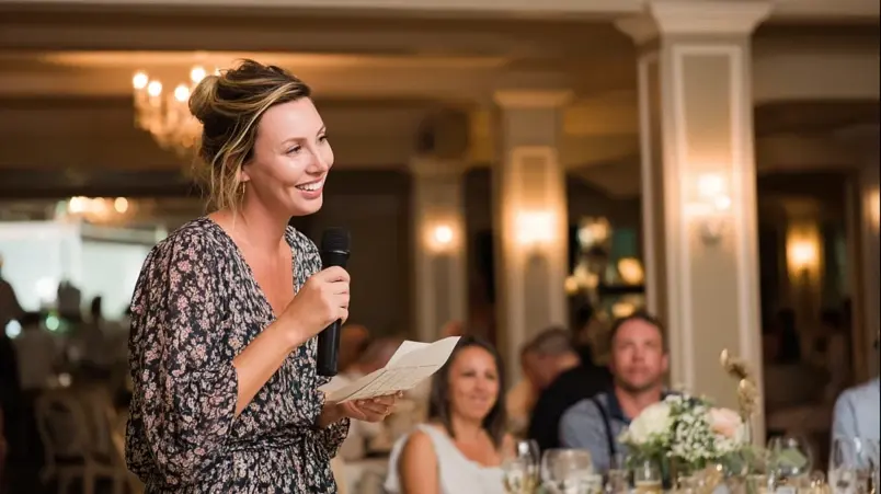 Talare som håller bröllopstal vid mikrofon under bröllopsmiddag