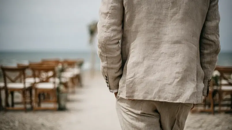 Ljus linnekostym i sandfärg på utomhusbröllop