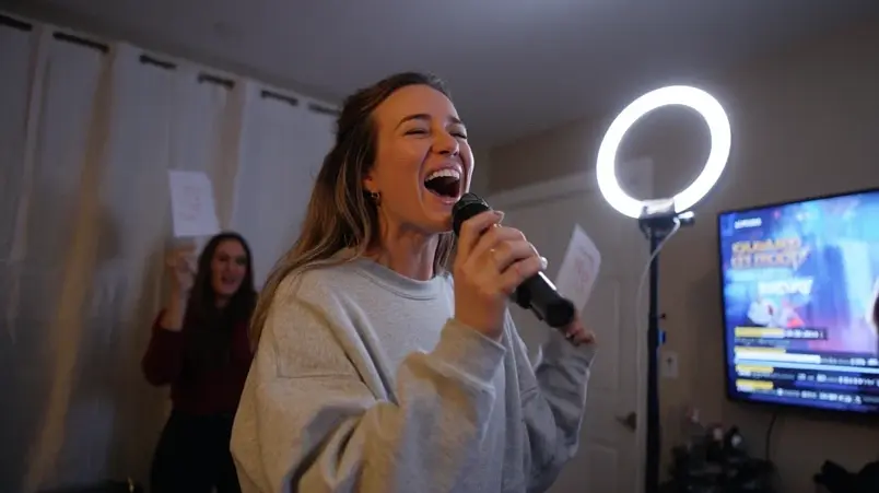 Kvinna som sjunger karaoke framför en ringlampa i ett vardagsrum
