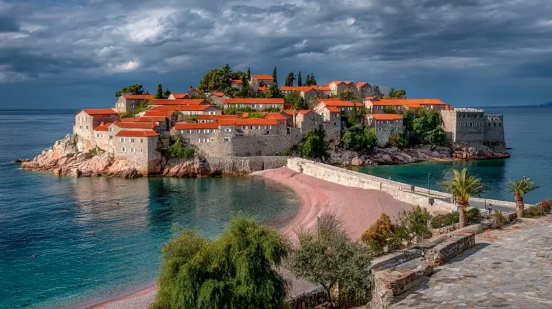 Sveti Stefan i Montenegro med kullerstensgator och rosaskimrande strand