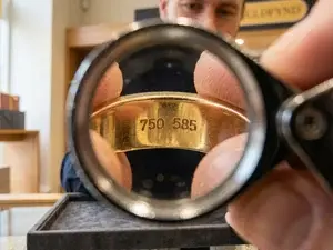 Guldringar på vit yta med förstoringsglas som visar stämplarna 750 och 585 på insidan av en ring.